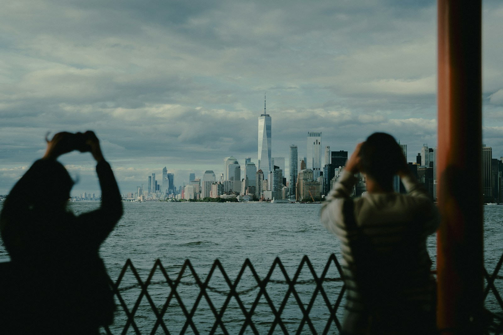 Photo by Lerone Pieters Two people photograph skyline from a boat.